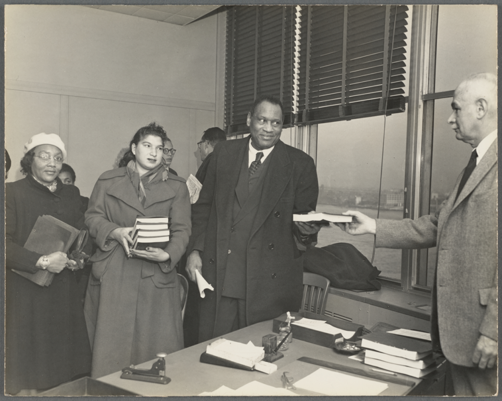 Paul Robeson hands a copy of the We Charge Genocide petition to a white UN official